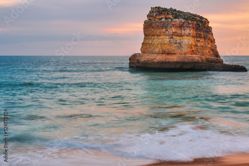 Rock at sunset light on famous beach of Praia dos Caneiros.