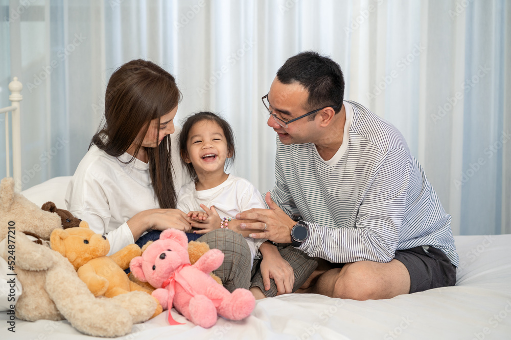 Happy young father and mother and a little daughter playing with Toy, sitting on the floor in living room, family, parenthood and people concept Happy young father and mother and a little daughter playing with Toy, sitting on the floor in living room, family, parenthood and people concept