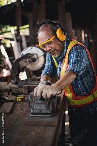An elderly carpenter works the wood with meticulous care.