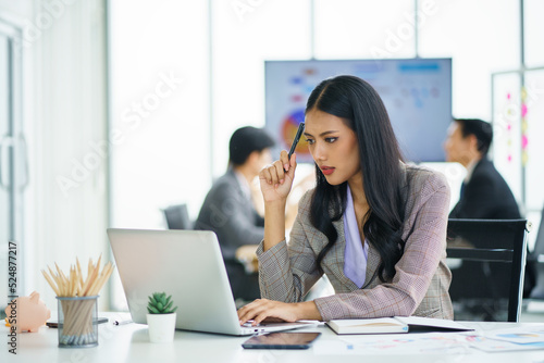 Young happy Asian businesswoman working and use a computer laptop and thinking idea for her business