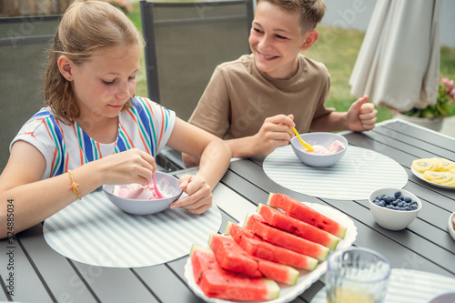 Teen brother and suster having breakfast outdoors