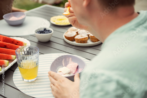 Young man eating ice-cream and sweets in outdoor cafe