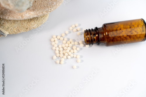 Homeopathy concept with white globules in glass bottle on white background