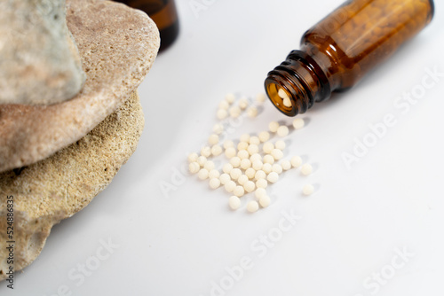Homeopathy concept with white globules in glass bottle on white background