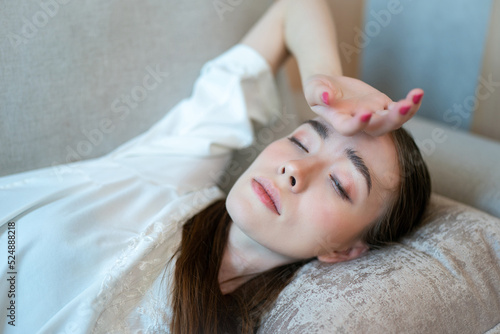 Young woman suffering from headache while resting on sofa at home