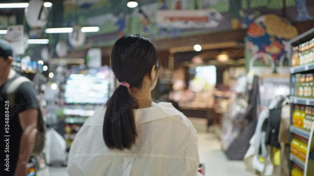 Busy woman walks past racks searching goods in supermarket Busy woman walks past racks searching goods in supermarket