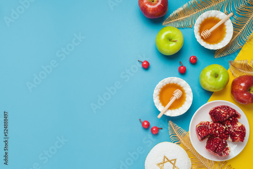 Fototapeta Naklejka Na Ścianę i Meble -  Jewish holiday Rosh Hashana banner design with honey, apple and pomegranate over blue background. Top view, flat lay