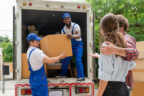 Man movers worker in blue uniform unloading cardboard boxes from truck.Professional delivery and moving service. photo