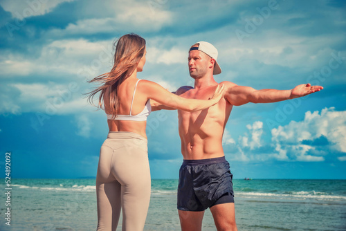Sport man and woman exercise on beach at daytime © nuttawutnuy
