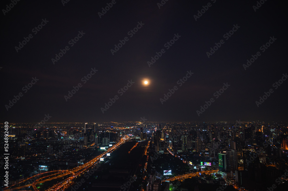 Fototapeta premium Bangkok.thailand.16.04.2022:Bangkok cityscape view with beautiful full moon from top of building in bangkok city