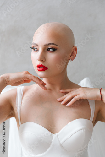 Bald beautiful bride in a luxurious wedding dress in red lipstick and a long veil is sick with cancer