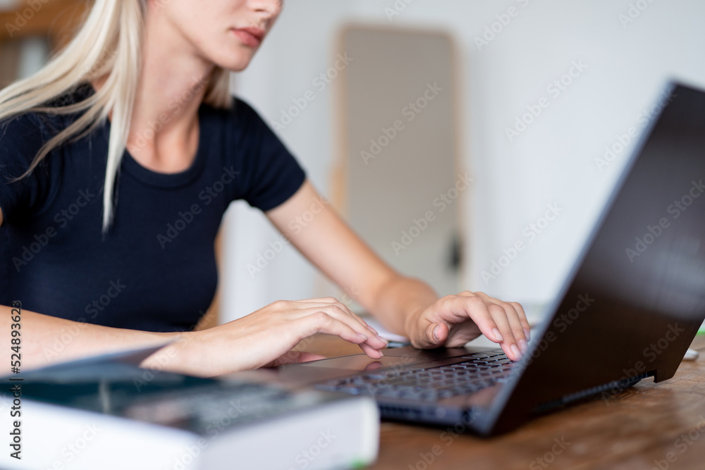 Fototapeta premium Woman sitting at table using laptop at home.
