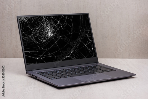 laptop with a broken screen in cracks on a gray background close up with clipping path