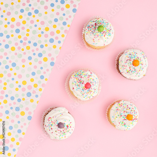 Birthday party cupcakes on pastel pink background. Flat lay