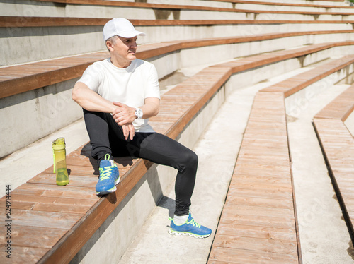 A retired sports man does a workout in the park, next to a bottle of water