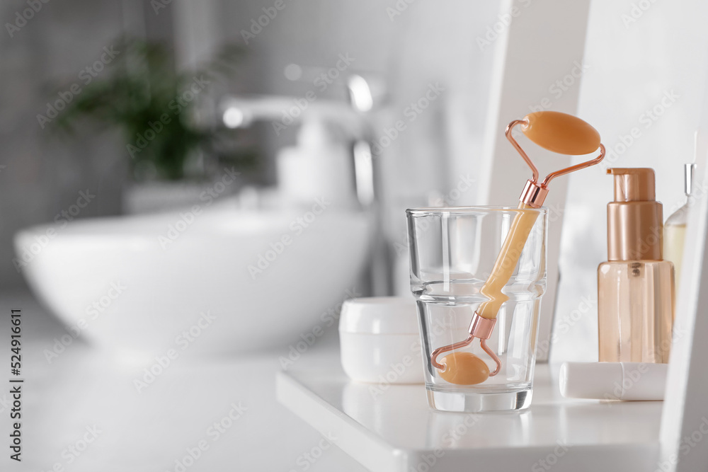 Natural face roller and cosmetic products on shelving unit in bathroom. Space for text Natural face roller and cosmetic products on shelving unit in bathroom. Space for text