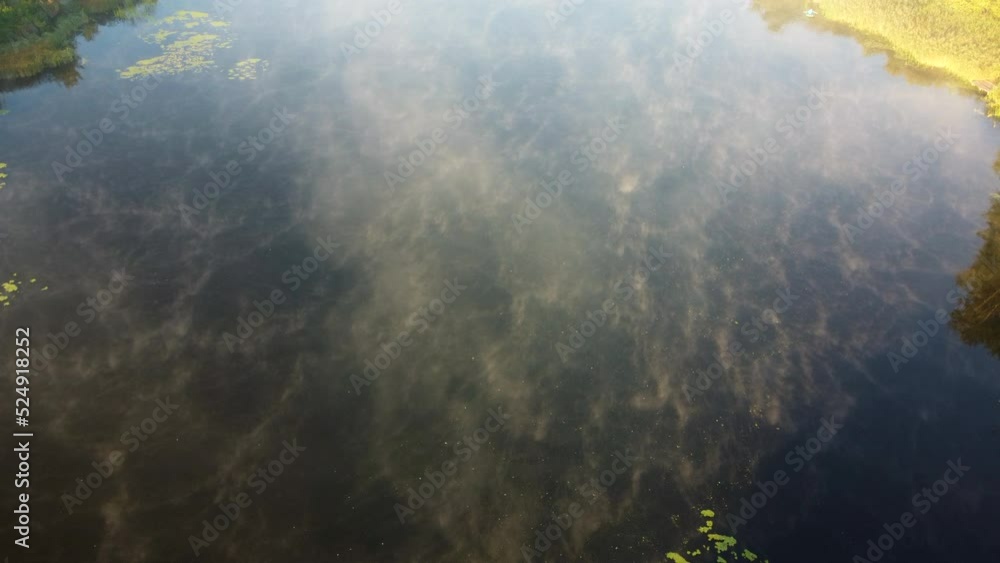 Aerial drone view flying over the river with calm reflective water surface and white fog mist and forest trees on the banks of the river on a sunny early autumn morning. Beautiful natural background. Aerial drone view flying over the river with calm reflective water surface and white fog mist and forest trees on the banks of the river on a sunny early autumn morning. Beautiful natural background.