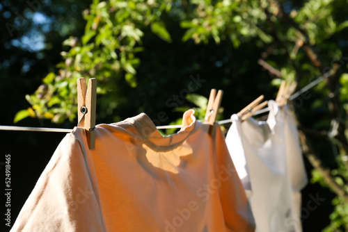 Obraz na płótnie Washing line with clean laundry and clothespins outdoors, closeup