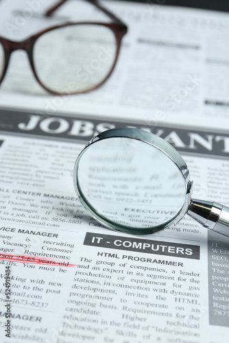 Magnifier and glasses on newspaper. Job search concept