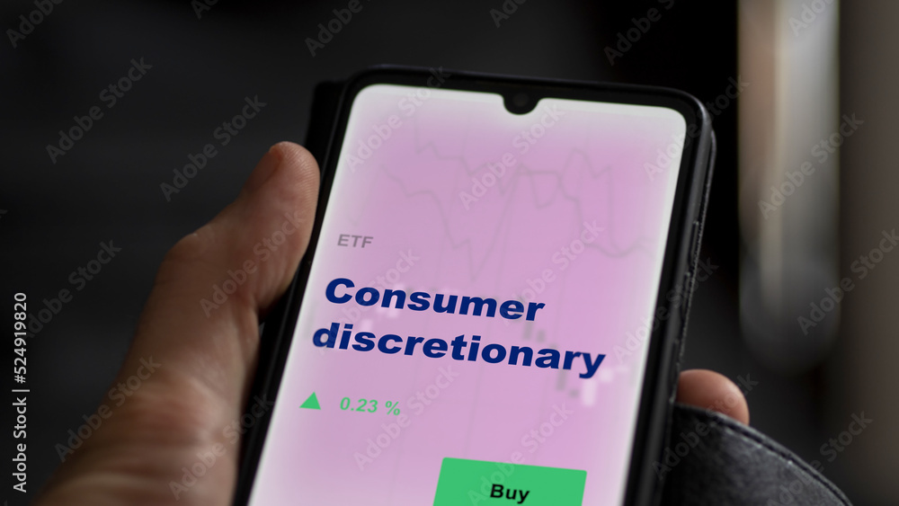 An investor's analyzing the consumer discretionary etf fund on screen. A phone shows the ETF's prices consumer basket to invest. An investor's analyzing the consumer discretionary etf fund on screen. A phone shows the ETF's prices consumer basket to invest.