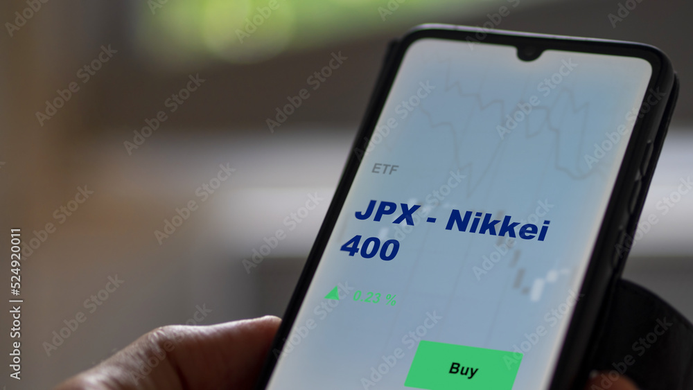 An investor's analyzing the JPX - Nikkei 400 etf fund on screen. A phone shows the ETF's prices Japan nikkei japan to invest An investor's analyzing the JPX - Nikkei 400 etf fund on screen. A phone shows the ETF's prices Japan nikkei japan to invest