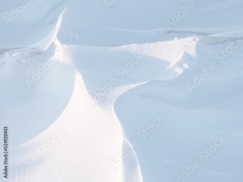 Snow texture. Wind sculpted patterns on snow surface. Wind in the tundra and in the mountains on the surface of the snow sculpts patterns and ridges (sastrugi). Arctic, Polar region. Winter background photo