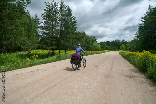 A cyclist rides on a road among fields, Bashkortostan, Russia.