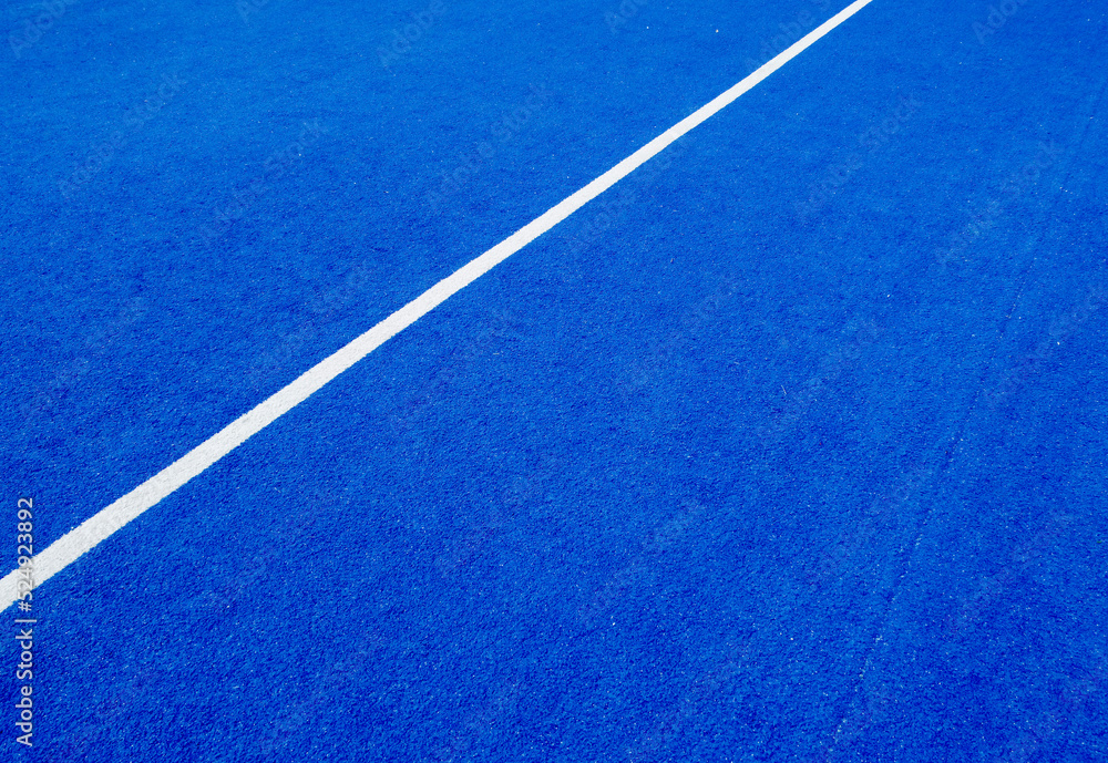 Fototapeta premium View of the net and the centre line of a blue paddle tennis court. Racket sports