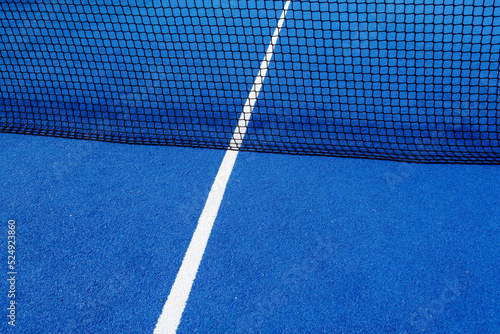 View of the net and the centre line of a blue paddle tennis court. Racket sports © Vic