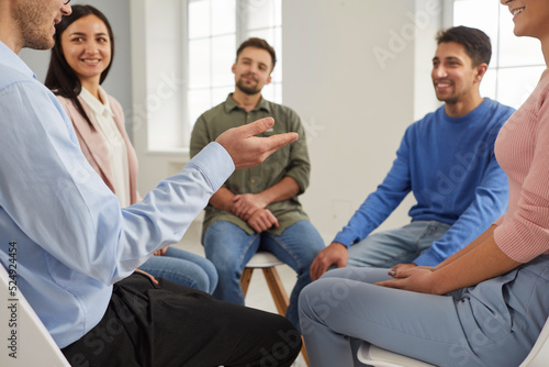 Group of people having a discussion during a business meeting in the office. Team of happy smiling employees sitting in a circle and talking. Young men and women discussing something in group therapy