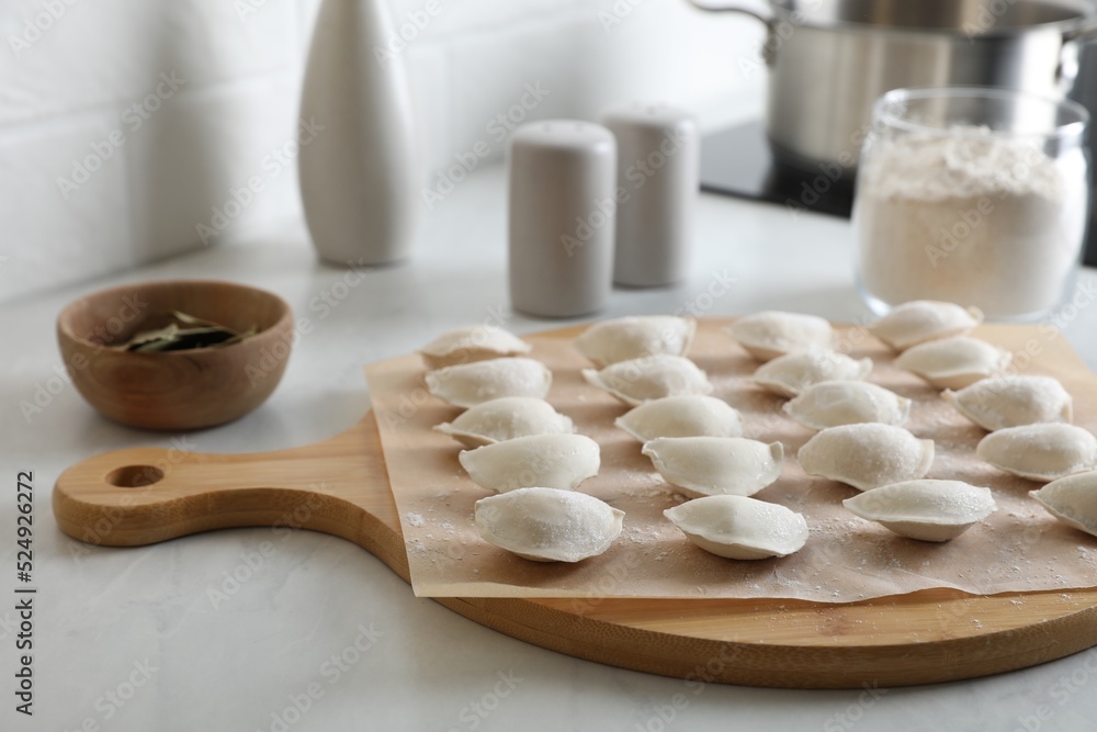 Fresh uncooked dumplings and flour on white table Fresh uncooked dumplings and flour on white table