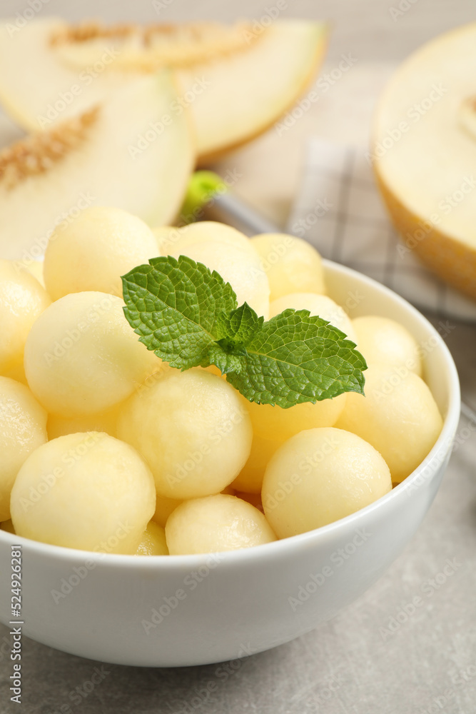 Melon balls and mint in bowl on light grey table, closeup