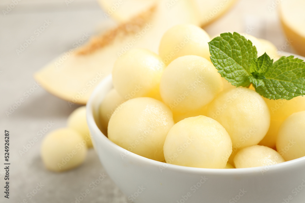 Melon balls and mint in bowl on light grey table, closeup. Space for text Melon balls and mint in bowl on light grey table, closeup. Space for text