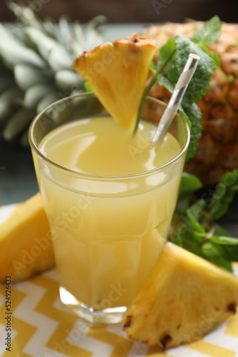 Delicious pineapple juice in glass and fresh fruit on table, closeup