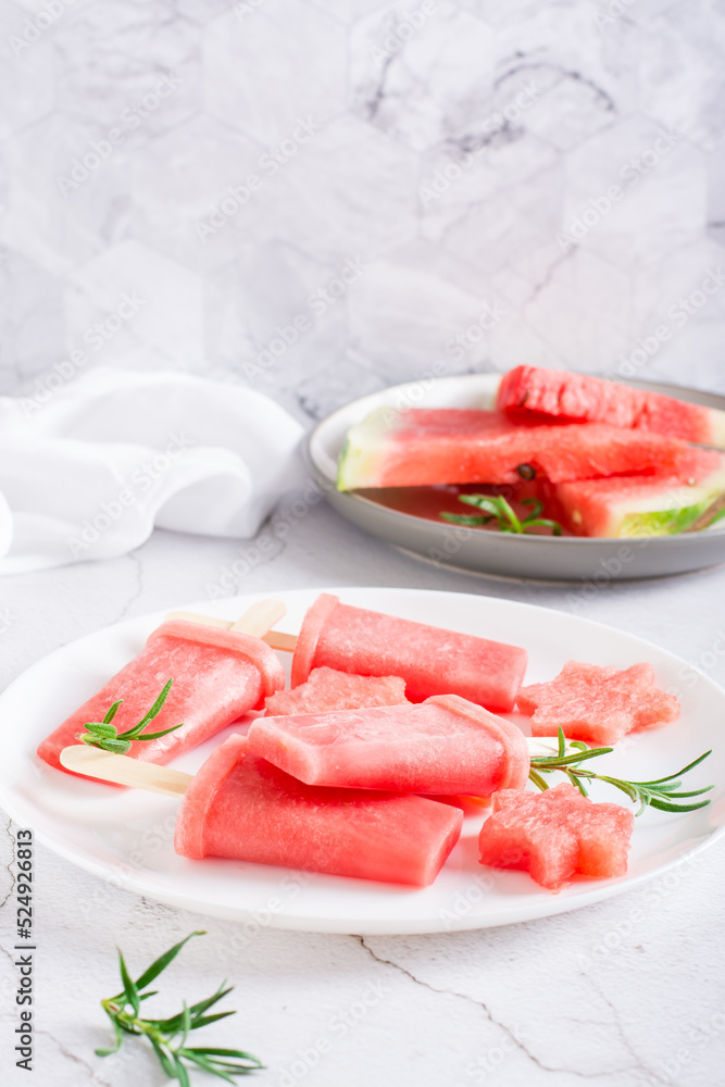 Watermelon popsicle and pieces of watermelon on a plate on the table. Homemade dessert. Vertical view