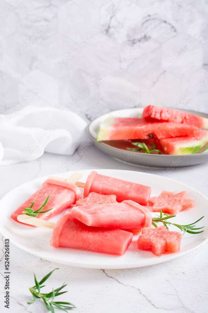 Watermelon popsicle and pieces of watermelon on a plate on the table. Homemade dessert. Vertical view Watermelon popsicle and pieces of watermelon on a plate on the table. Homemade dessert. Vertical view
