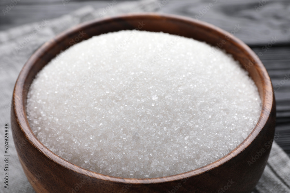 Granulated sugar in wooden bowl on table, closeup Granulated sugar in wooden bowl on table, closeup