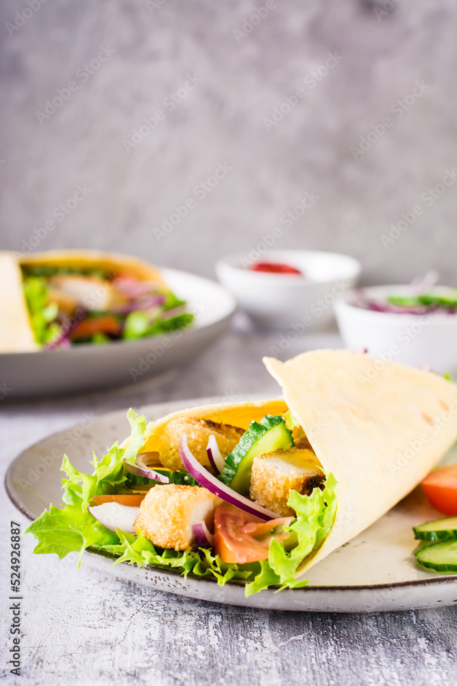 Tortilla wrap with cucumber, chicken and tomato on a plate. Mexican cuisine. Vertical view