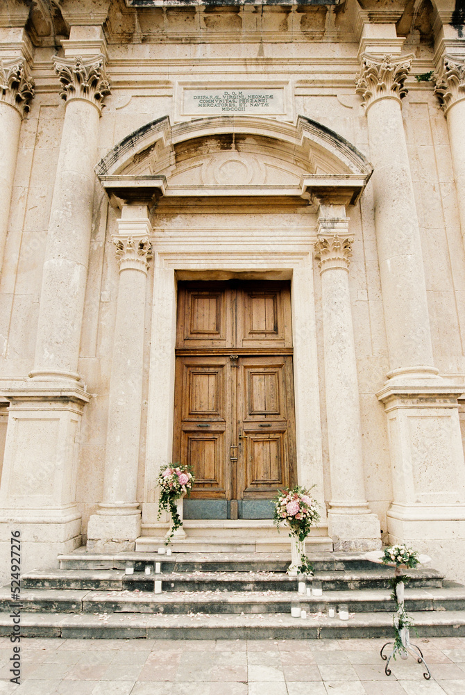 Pedestals with flowers stand on the steps of the church