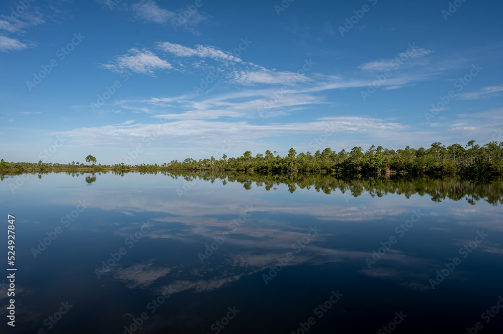 Early morning summer cloudscape over Pine Glades Lake in Everglades National Park, Florida reflected in calm lake water.