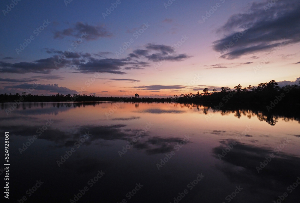 Colorful summer sunset cloudscape over Pine Glades Lake reflected in calm water of Everglades National Park, Florida.