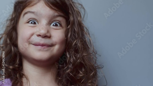 Portrait of a cute toddler girl making funny faces. 4K footage. photo