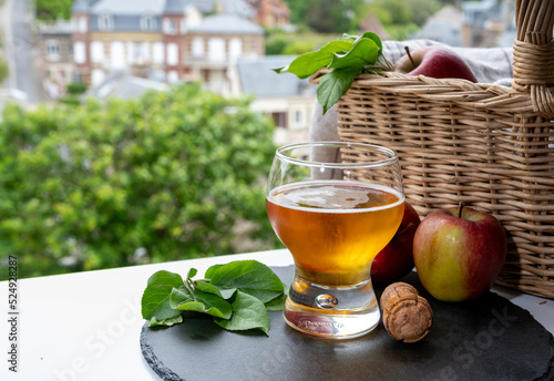 Glass of cold apple cider drink and houses of Etretat village on background, Normandy, France photo