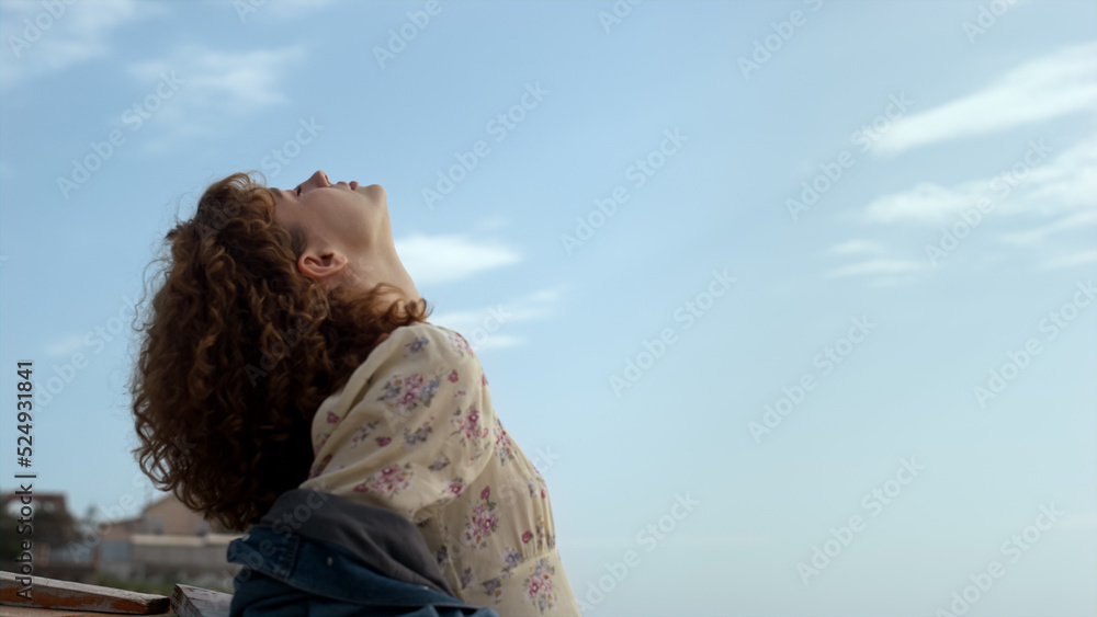 Fototapeta premium Serene girl standing beach raising face to sunlight closeup. Lady enjoy seascape
