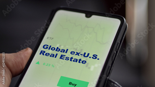 An investor's analyzing the global ex-U.S. real estate etf fund on screen. A phone shows the ETF's prices global ex u.s. real estate to invest