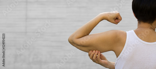 A faceless woman shows the flabby muscles of the arm with her index finger. Flabby Arm Syndrome (FAS). Effect of aging caused by loss of elasticity and muscle. Banner, copyspace.