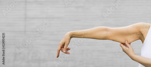 A woman shows the flabby muscles of the arm . Flabby Arm Syndrome (FAS). Effect of aging caused by loss of elasticity and muscle.Banner, copyspace. photo