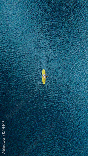 Aerial image of kayaking. Straight above drone shot. Yellow kayak and blue water.