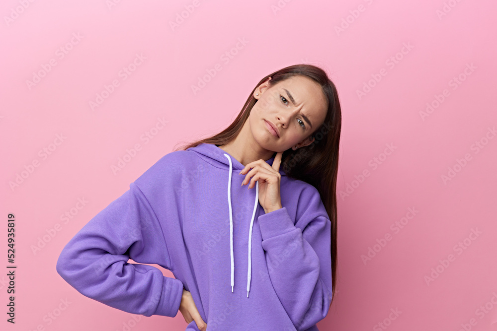 a frowning woman stands looking forward against a pink background in a purple suit, frowning slightly and leaning her finger against her cheek a frowning woman stands looking forward against a pink background in a purple suit, frowning slightly and leaning her finger against her cheek