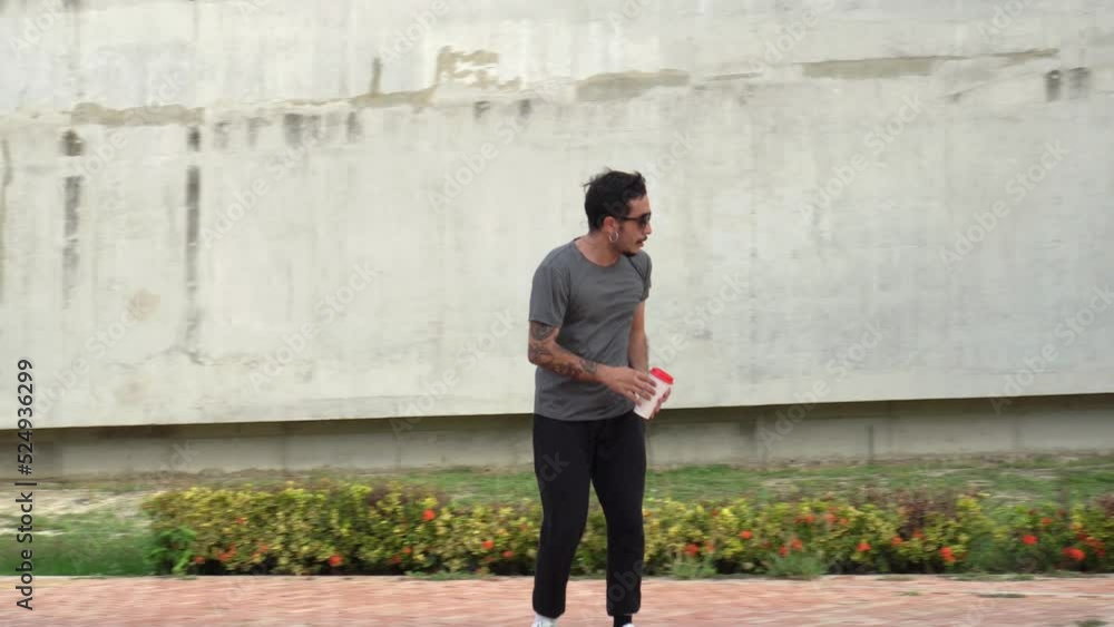 Young man riding a skateboard and carrying a drink Young man riding a skateboard and carrying a drink